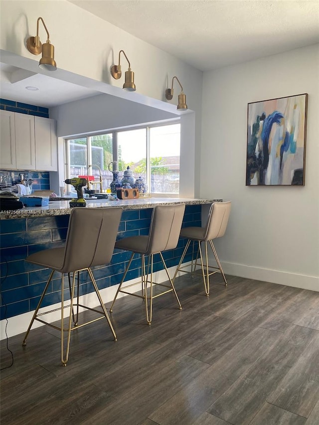 interior space with white cabinetry, kitchen peninsula, a kitchen bar, and light stone countertops