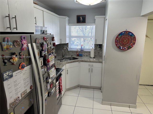 kitchen featuring light stone countertops, stainless steel appliances, white cabinetry, light tile patterned flooring, and sink