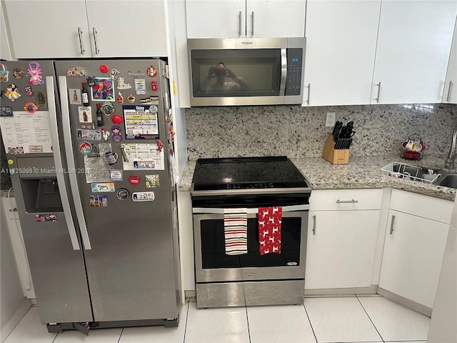 kitchen with stainless steel appliances, light stone countertops, decorative backsplash, white cabinets, and sink