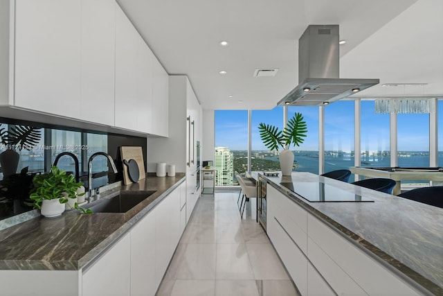 kitchen with sink, white cabinets, a water view, island exhaust hood, and dark stone counters