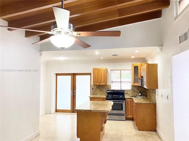 kitchen with light stone counters, stainless steel range, sink, and backsplash