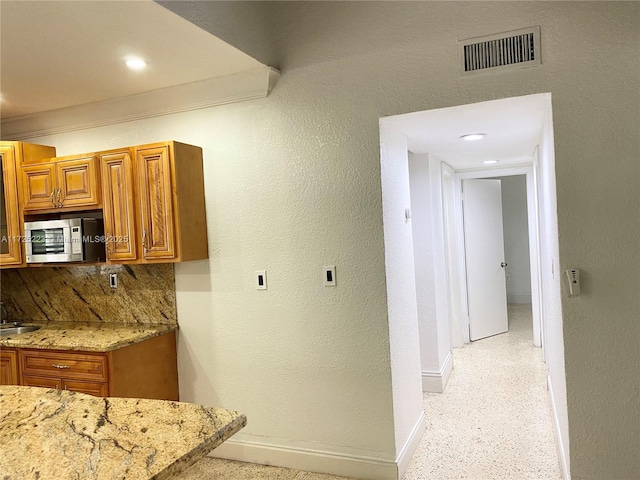 kitchen featuring tasteful backsplash, light stone countertops, and sink