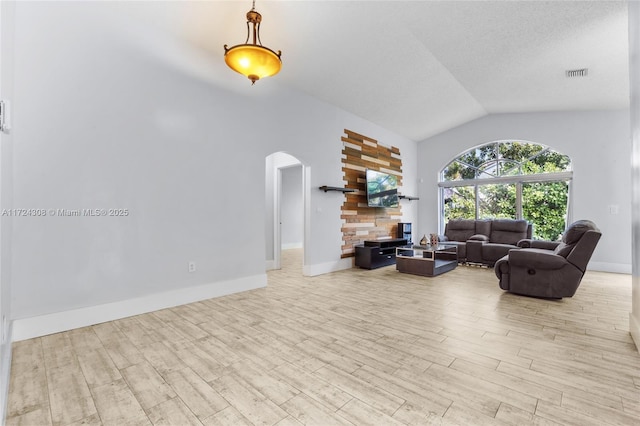 living room with light hardwood / wood-style floors, vaulted ceiling, and a textured ceiling