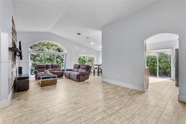 living room featuring light wood-type flooring, a textured ceiling, and vaulted ceiling