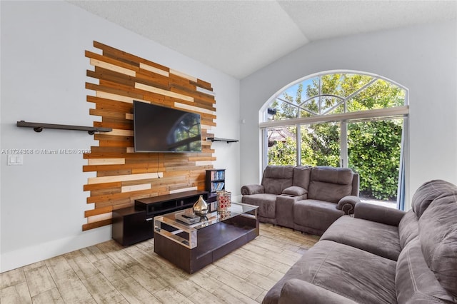 living room featuring vaulted ceiling, wood walls, a wealth of natural light, and light hardwood / wood-style flooring