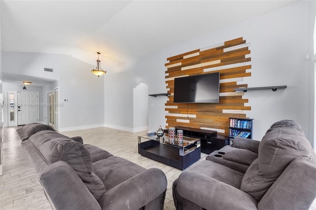 living room with lofted ceiling, wood walls, and light hardwood / wood-style floors