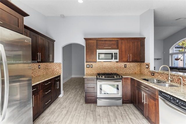 kitchen featuring sink, stainless steel appliances, light stone counters, and tasteful backsplash