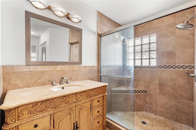 bathroom featuring tile walls, a shower with shower door, and vanity