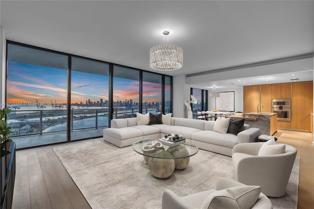 living room with floor to ceiling windows, light hardwood / wood-style floors, a chandelier, and sink