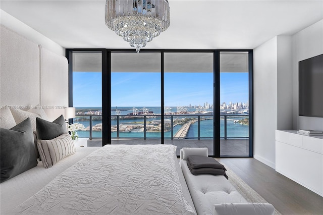 bedroom with floor to ceiling windows, multiple windows, hardwood / wood-style floors, and a water view