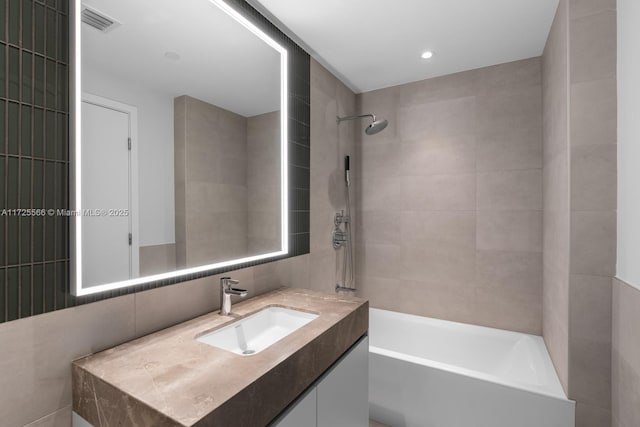 bathroom featuring vanity, tile walls, and tiled shower / bath combo