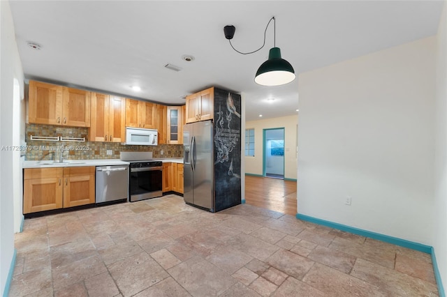 kitchen featuring appliances with stainless steel finishes, hanging light fixtures, decorative backsplash, and sink