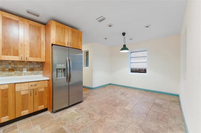 kitchen featuring pendant lighting, stainless steel fridge with ice dispenser, and tasteful backsplash