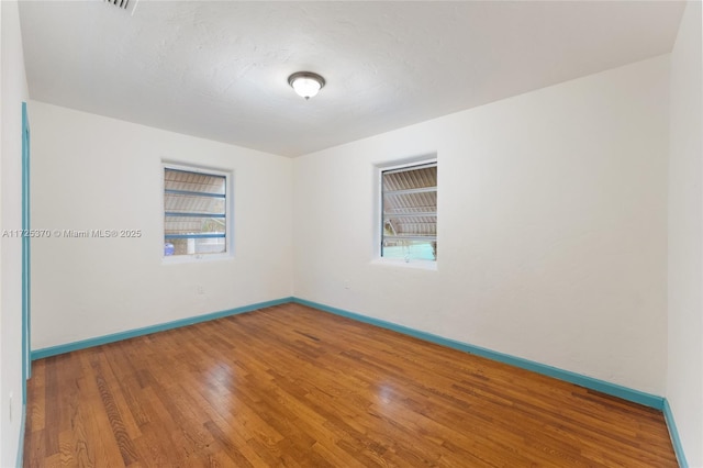 empty room with hardwood / wood-style floors and a healthy amount of sunlight