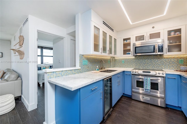 kitchen featuring stainless steel appliances, light stone counters, sink, white cabinetry, and backsplash