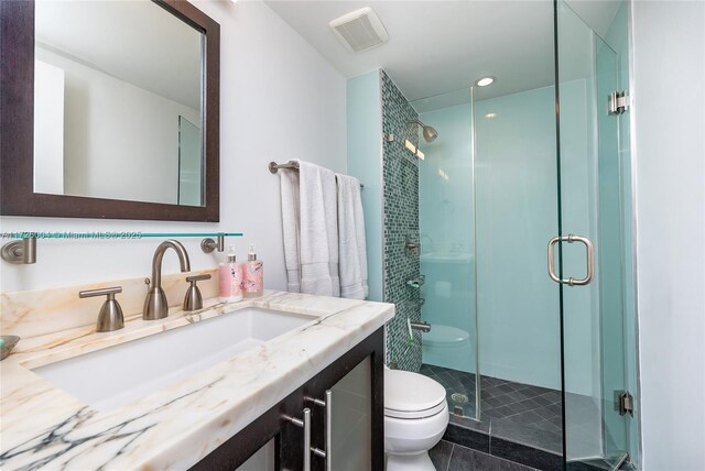 bathroom featuring a shower with door, vanity, and toilet