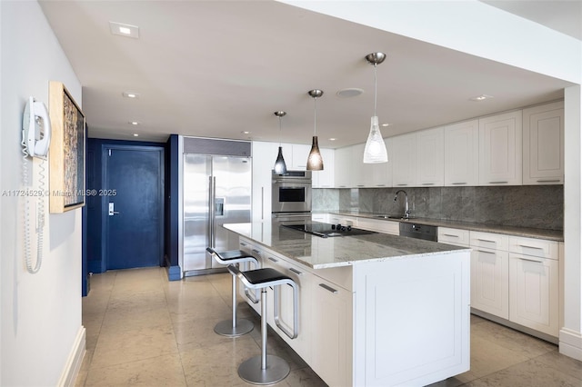 kitchen featuring decorative light fixtures, a center island, white cabinetry, light stone counters, and black appliances