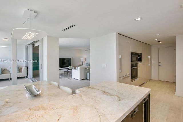 kitchen featuring decorative light fixtures, white cabinets, light stone countertops, and light hardwood / wood-style flooring