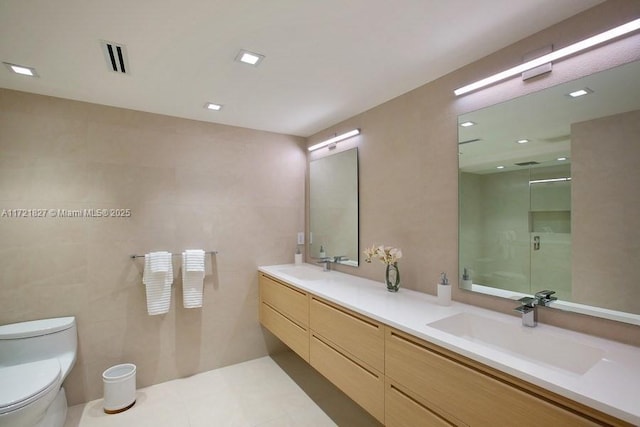 bathroom with toilet, tile patterned floors, vanity, tile walls, and an enclosed shower