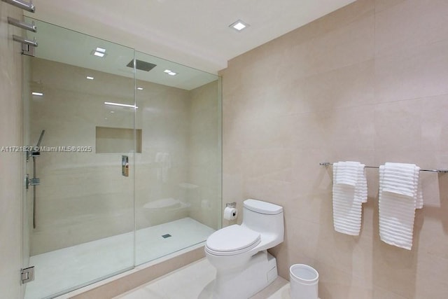 bathroom with tile walls, a shower with door, and toilet