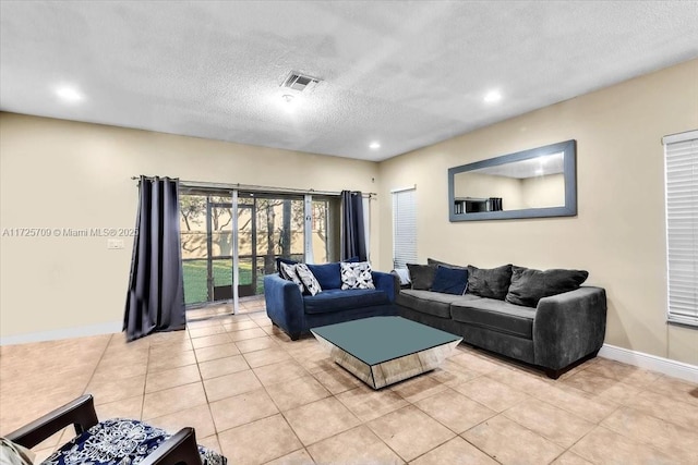 living room with a textured ceiling and light tile patterned floors