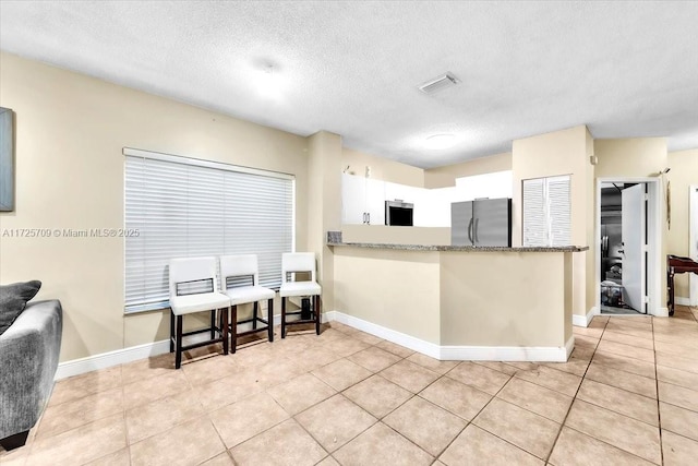 kitchen with appliances with stainless steel finishes, white cabinets, and light tile patterned flooring