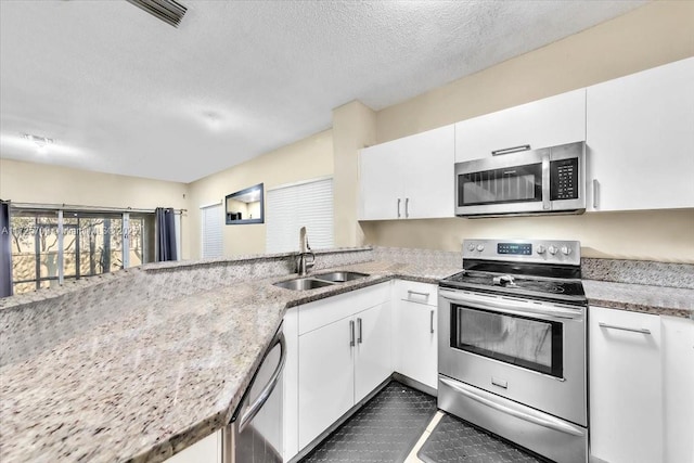 kitchen with appliances with stainless steel finishes, kitchen peninsula, white cabinets, and sink