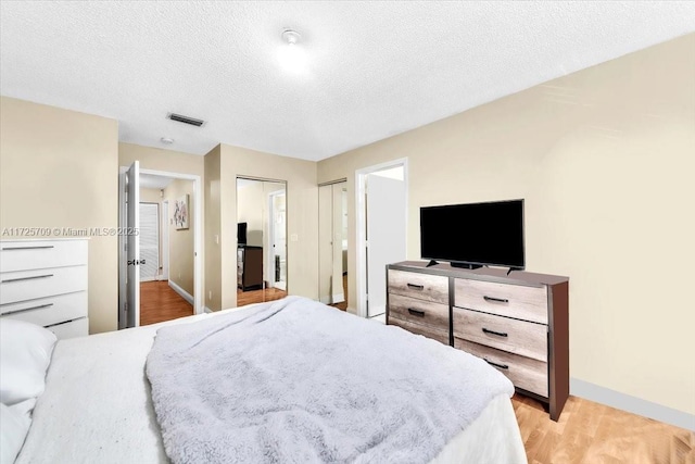 bedroom with a textured ceiling and light hardwood / wood-style flooring