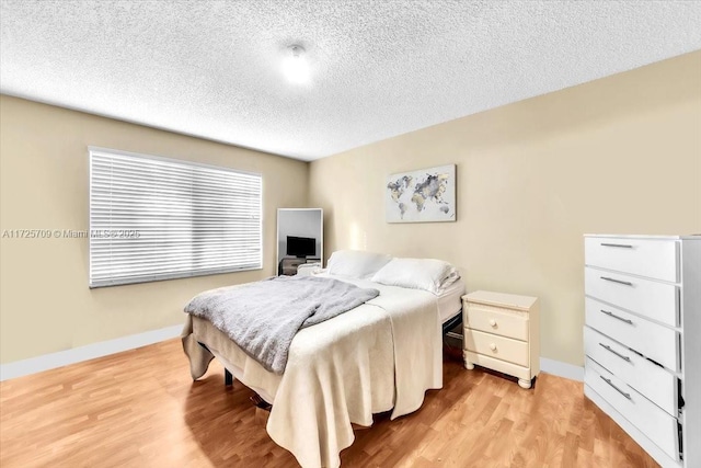 bedroom with a textured ceiling and light hardwood / wood-style flooring