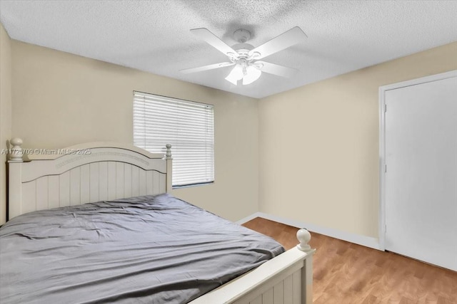 bedroom featuring ceiling fan, light wood-type flooring, and a textured ceiling