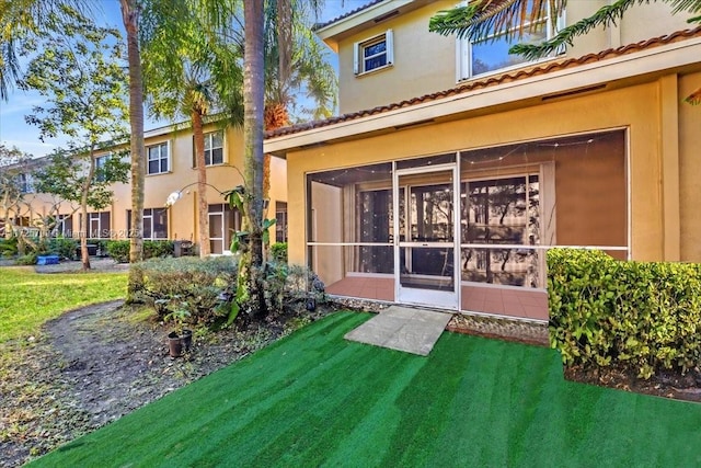 rear view of property featuring a lawn and a sunroom