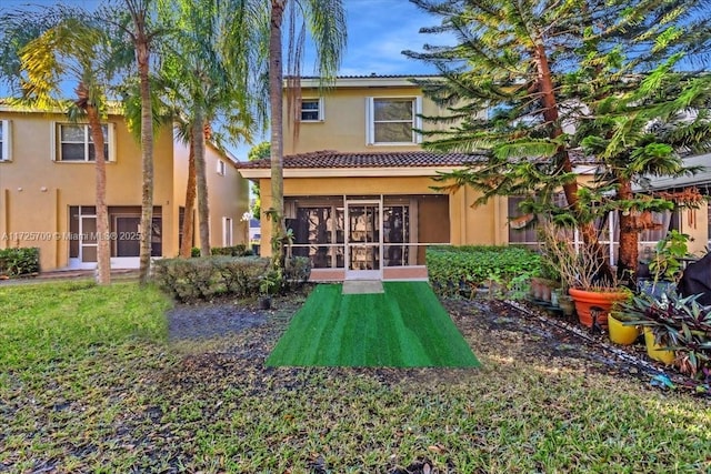 back of property featuring a yard and a sunroom