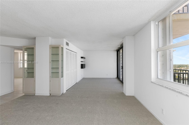 hallway with light colored carpet and a textured ceiling