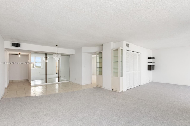 interior space with a textured ceiling, light colored carpet, and an inviting chandelier