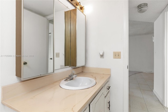 bathroom with a textured ceiling, tile patterned flooring, and vanity