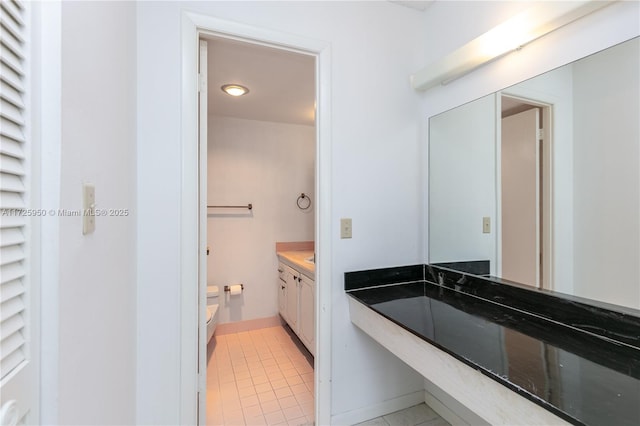 bathroom with toilet, vanity, and tile patterned floors