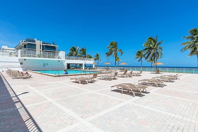 view of swimming pool featuring a patio and a water view