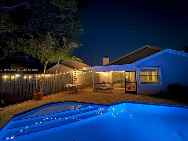 pool at twilight featuring a patio area