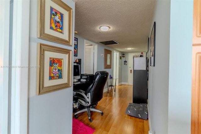 home office with a textured ceiling and light wood-type flooring