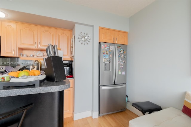 kitchen with light wood-type flooring, stainless steel fridge, and light brown cabinets