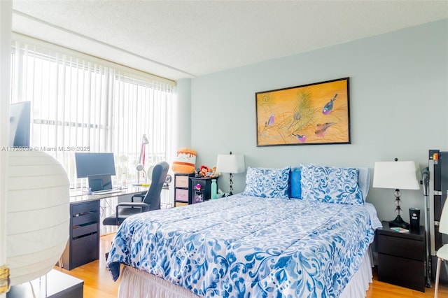 bedroom with a wall of windows, a textured ceiling, and light wood-type flooring