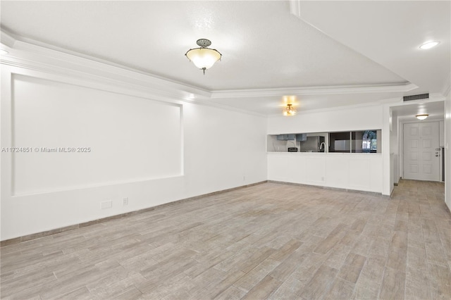 unfurnished living room with ornamental molding, a tray ceiling, and light hardwood / wood-style floors