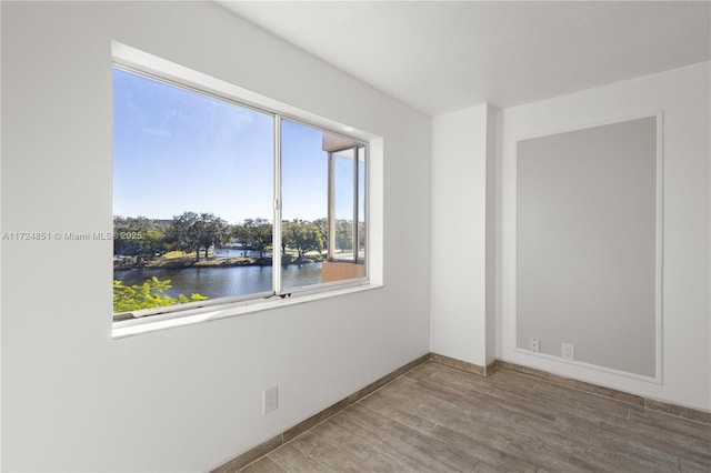 spare room with hardwood / wood-style floors and a water view