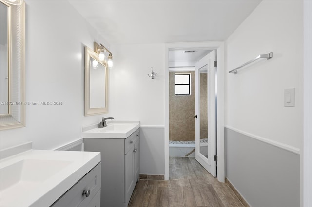 bathroom with a tile shower, vanity, and hardwood / wood-style flooring