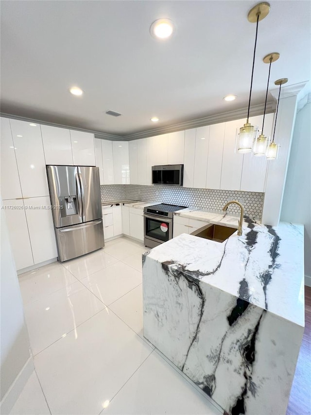 kitchen featuring sink, white cabinets, backsplash, pendant lighting, and appliances with stainless steel finishes