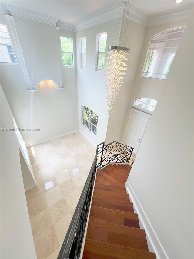 staircase with crown molding, a chandelier, and heating unit