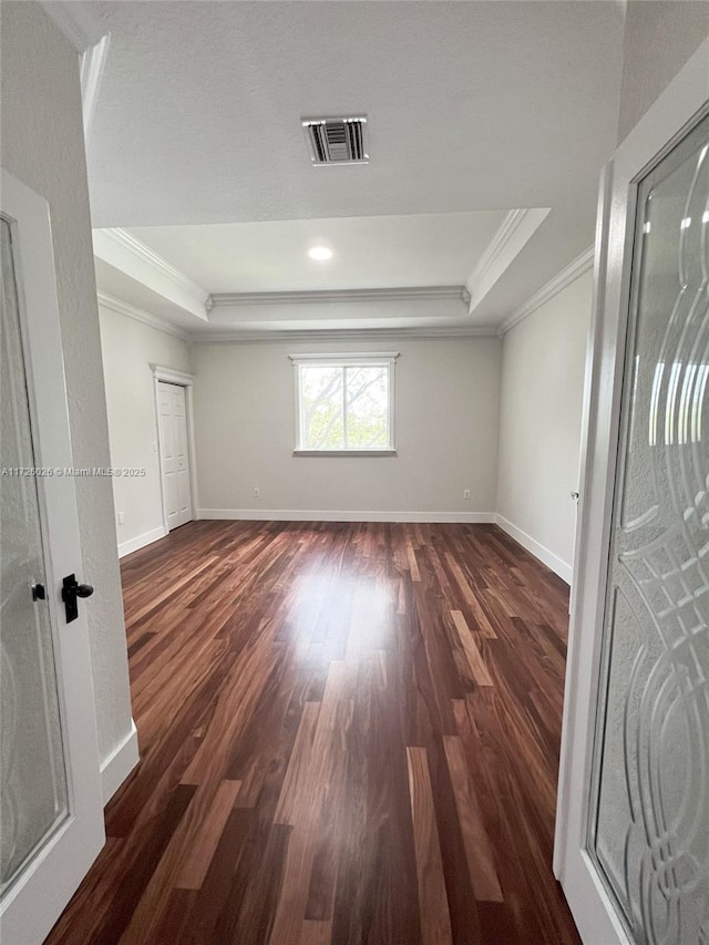 spare room with dark hardwood / wood-style flooring, crown molding, and a tray ceiling