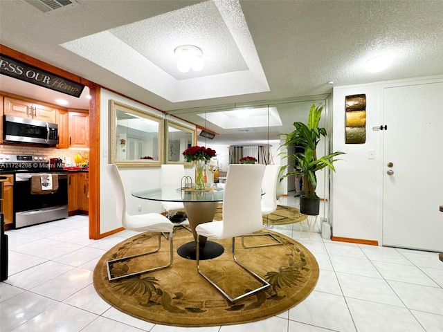 tiled dining room with a raised ceiling and a textured ceiling