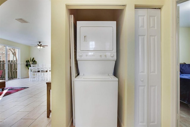 laundry room with stacked washer / dryer, light tile patterned floors, and ceiling fan