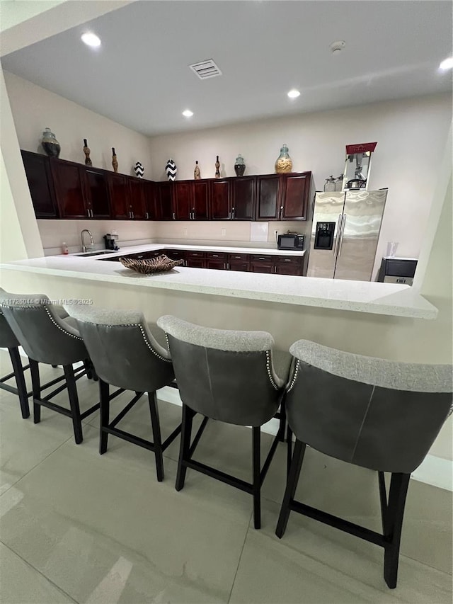 kitchen featuring stainless steel refrigerator with ice dispenser, a kitchen breakfast bar, and kitchen peninsula